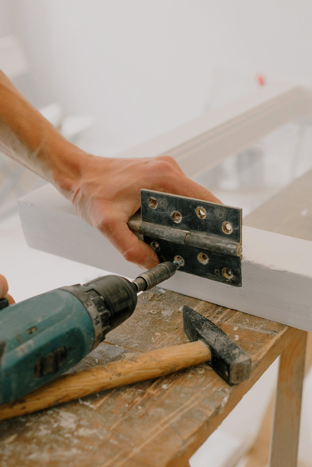 Crop handyman fastening metal hinge on white window